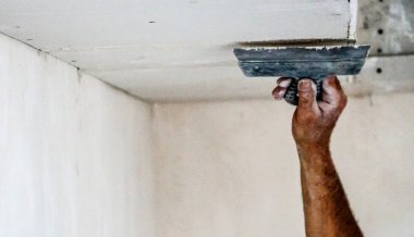 Bir adam bitmemiş beyaz bir duvar çiziyor.