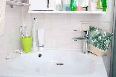 lavabo ve musluk modern banyo içi akan suyla, diş fırçaları kozmetikle