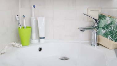 lavabo ve musluk modern banyo içi akan suyla, diş fırçaları kozmetikle