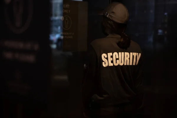 A female security guard is walking through an automated curved revolving sliding door to patrol a commercial area. fpsecurity.ca