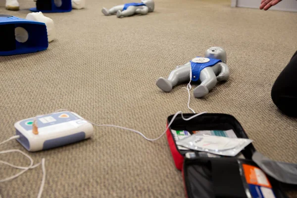 Staff practicing first aid cpr with their fingers and AED machine