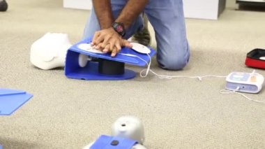Staff is training to conduct first aid CPR with a dummy doll and AED machine
