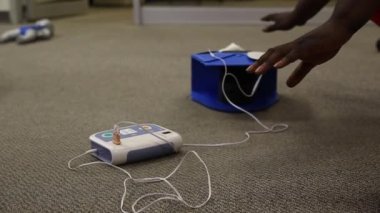 Staff is training to conduct first aid CPR with a dummy doll and AED machine