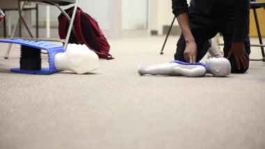 Staff is training to conduct first aid CPR with a dummy doll and AED machine