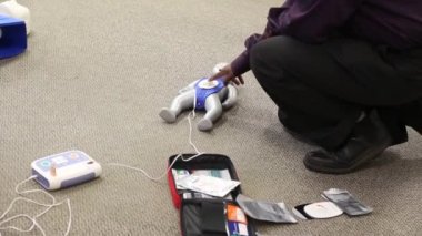 Staff is training to conduct first aid CPR with a dummy doll and AED machine