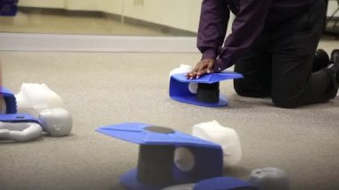 Staff is training to conduct first aid CPR with a dummy doll and AED machine
