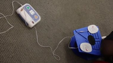 Staff is training to conduct first aid CPR with a dummy doll and AED machine