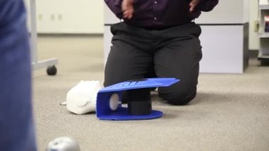 Staff is training to conduct first aid CPR with a dummy doll and AED machine