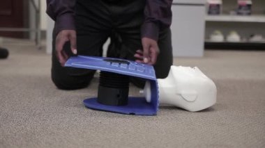 Staff is practicing CPR first aid with the AED with adult and infant dummy dolls.