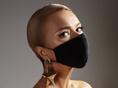 Siyah Yüzlü Güzel Kadın. Moda Göz Makyajı ve Altın Aksesuarlar. Virüs salgınında hijyen koruması