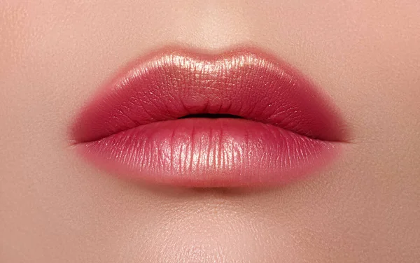 Parlak kırmızı dudaklar altın parıltısıyla süslenmiş göz kamaştırıcı moda. Makro kadın yüzü parçası. Seksi dudak makyajı, lüks bir yüz.