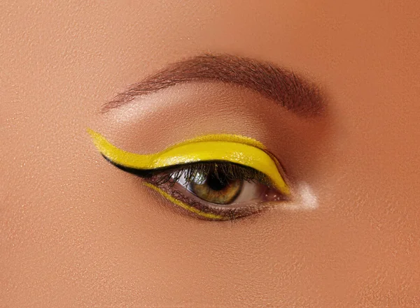 Ojo femenino de cerca con maquillaje de delineador amarillo brillante. Maquillaje Neon Disco y Manicura de Moda. Estilo de belleza de verano — Foto de Stock