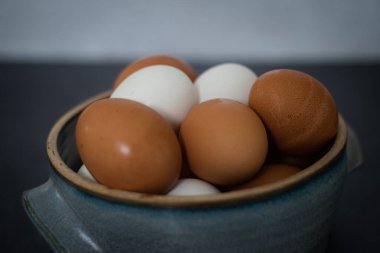 Yan tarafı kapat. Beton duvarlı, kahverengi ve beyaz yumurtalardan oluşan el yapımı seramik kasenin yan görüntüsü. Yüksek kalite fotoğraf. Mavi seramik kase.