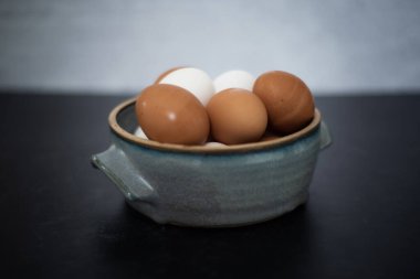 Üst Manzara. Beton duvarlı, kahverengi ve beyaz yumurtalardan oluşan el yapımı seramik kasenin yan görüntüsü. Yüksek kalite fotoğraf. Çok basit. Sağlıklı. Pişirme, pişirme. Karışık yumurta. Mavi seramik kase.