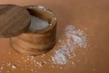 Turuncu terasotta arka planındaki ahşap tuz kabının içindeki organik deniz tuzu yığınının en üst görüntüsü. Yüksek kalite fotoğraf. Çok basit. Sağlıklı. Pişirme, pişirme.