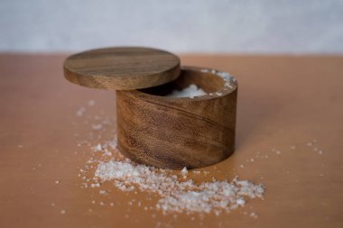 Turuncu terakotta beton zemin üzerinde ahşap tuz kabının içindeki organik deniz tuzu yığınının yan görüntüsü. Yüksek kalite fotoğraf. Çok basit. Sağlıklı. Pişirme, pişirme.