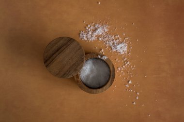 Turuncu terasotta arka planındaki ahşap tuz kabının içindeki organik deniz tuzu yığınının en üst görüntüsü. Yüksek kalite fotoğraf. Çok basit. Sağlıklı. Pişirme, pişirme.