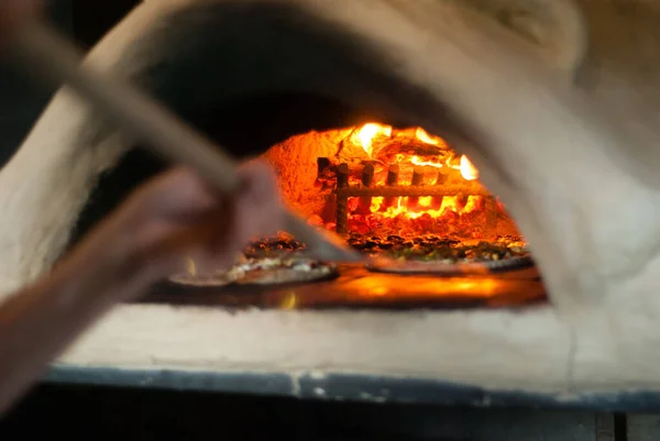 Wood fired pizza being cooked inside hot wood fired pizza oven. Natural. Food. High quality photo.