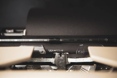 Siyah kağıt ve beyaz mürekkeple klasik sözcüğü gösteren klasik bir daktilo. Karanlık arka plan. Yüksek kalite fotoğraf