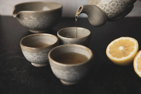 Pouring Korean tea into teacups with lemon and loose leaf tea. High quality photo