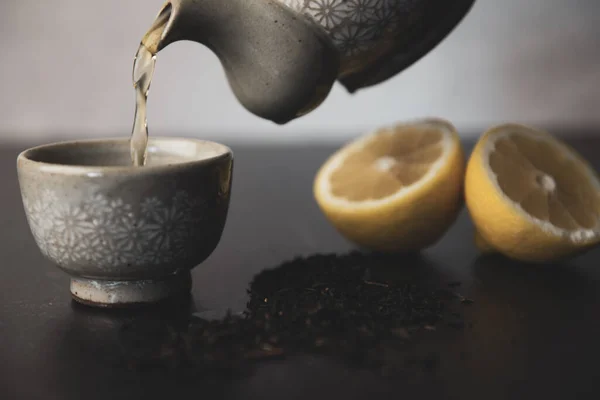 Pouring Korean tea into teacups with lemon and loose leaf tea. High quality photo