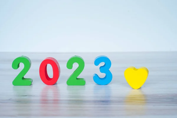 2023 standing colored block numbers on light wooden and white background. High quality photo