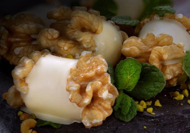 Beyaz çikolata ve ceviz kabuğundan yapılmış el yapımı tatlılar koyu bir arka planda yansıma ve ceviz çekirdekleri ile doluyor.