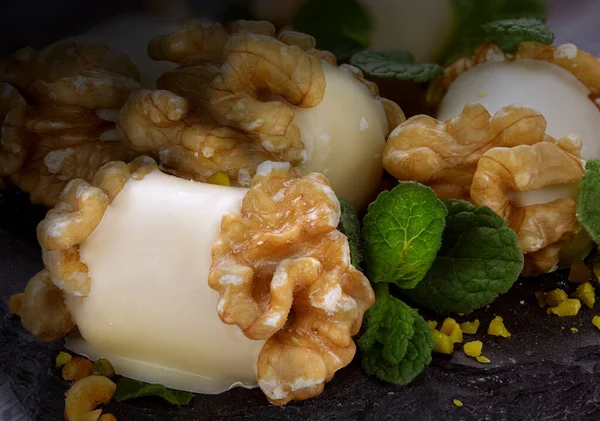 Beyaz çikolata ve ceviz kabuğundan yapılmış el yapımı tatlılar koyu bir arka planda yansıma ve ceviz çekirdekleri ile doluyor.