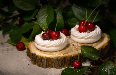 Beyaz krema, kiraz üzümlü krema kahverengi ahşap bir masa ve kiraz yaprakları üzerinde ahşap bir kesim