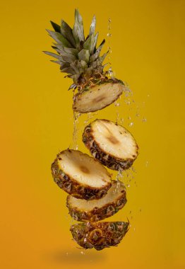 Uçan ananas, dilimler halinde dilimler halinde dilimler halinde sarı parlak arkaplanda ananas suyu.