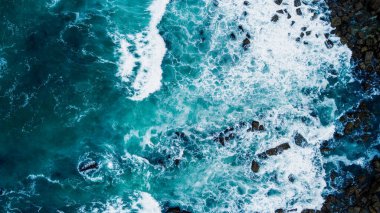 Kıyı uçurumunda, bulutlu bir ilkbahar gününde kayalıklarda kırılan dalgaların sarhoş görüntüsü.