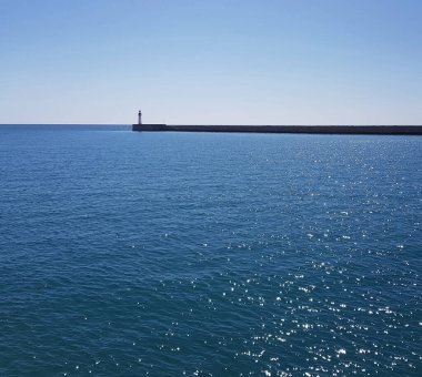 Deniz kenarında taş işlemeli ve mavi gökyüzüyle deniz feneri izolasyonu.