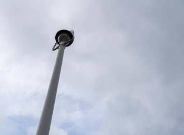 Bulutlu gökyüzünün altından beyaz sokak lambası