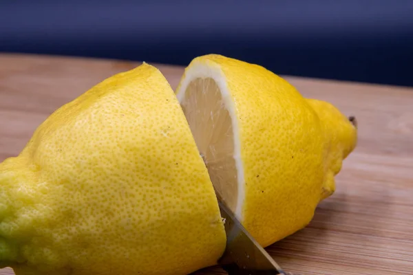 Siyah arka planda kesme tahtasında bıçakla limon kesen adamın elleri