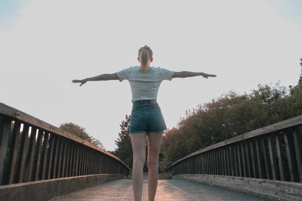 close-up of girl exercising on wooden bridge. Tranquility at sunset.