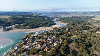Güneşli bir yaz gününde Cantabrian sahilinin arka planında köyün ve plajın insansız hava görüntüsü..