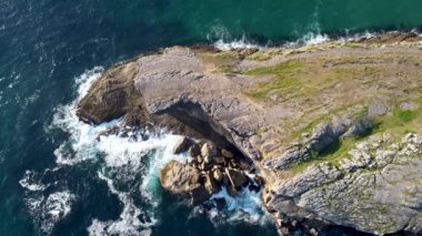 Dalgaların güneşli bir günde kayalara çarptığı Cantabrian kıyılarının insansız hava görüntüsü.