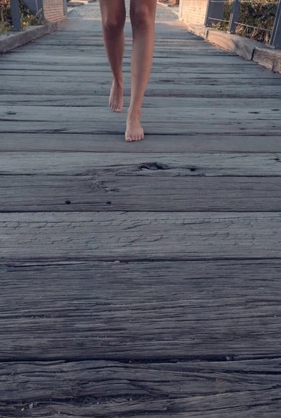 Blonde-haired woman strolling relaxed on wooden bridge de-stressing from city life