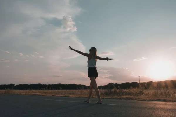blonde-haired woman walking on the road at sunset in shorts
