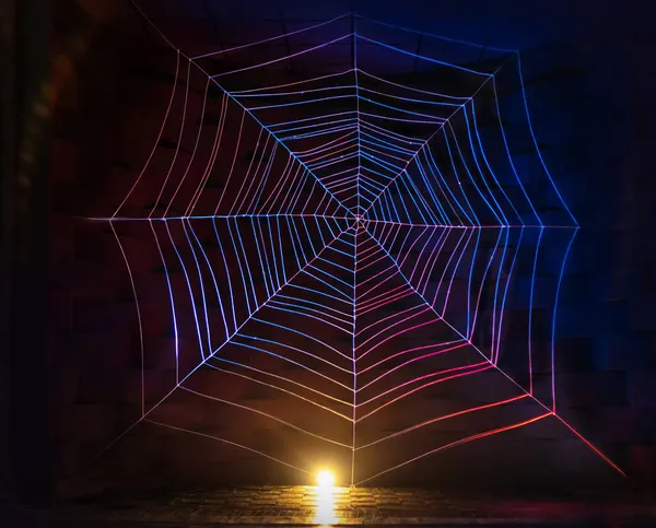 Celebration halloween holiday backdrop, huge white multicolored rainbow in neon light spider web. Gothic abstract Cobweb texture on black background in dark studio room. Festive party. Free space Stock Picture