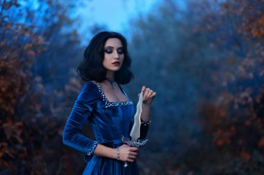 Fantezi ortaçağ savaşçı kraliçesi elinde hançer, elinde bıçak. Kraliyet kadifesi, inci kolyeli mavi elbise, kız prenses vampir, esmer kısa saç. Doğa Ormanı Alacakaranlık Gecesi, Sonbahar Mevsimi