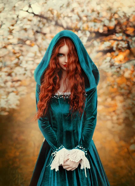 Portrait mystical fantasy red-haired woman witch looking at camera. Girl princess. Blue green medieval Victorian dress. Glamorous lady queen, red long curly hair waving flying in wind. Autumn forest. — Photo