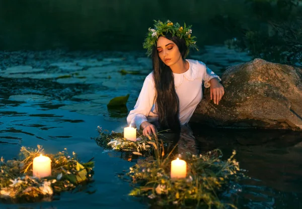 Slaviska kvinna nymf står i vatten ört krans floa ljus brinner. Fantasy flicka sjöjungfru. Vit lång våt klänning. Sommar natt grönt gräs träd flod. hednisk semester Ivan Kupala spådomar jungfrur — Stockfoto