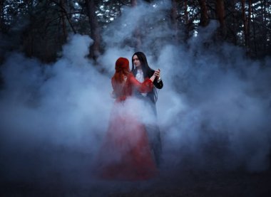 Gürültülü resim. Gotik çift, peri masalı karanlık gece ormanlarının arka planında dans ediyor. Kadın seksiliğini geri çevirdi. Vampir uzun siyah saçlı adam, prenses vampiri baştan çıkarıyor. Ağaçlar mavi sis dumanı.