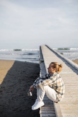 İtalya 'da Adriyatik Denizi' nin kıyısındaki iskelede elinde bardak tutan adamın yan görüntüsü 