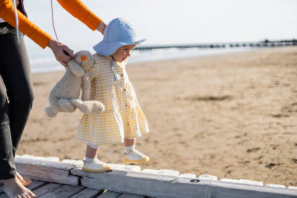Woman holding toy near toddler daughter on pier in Treviso