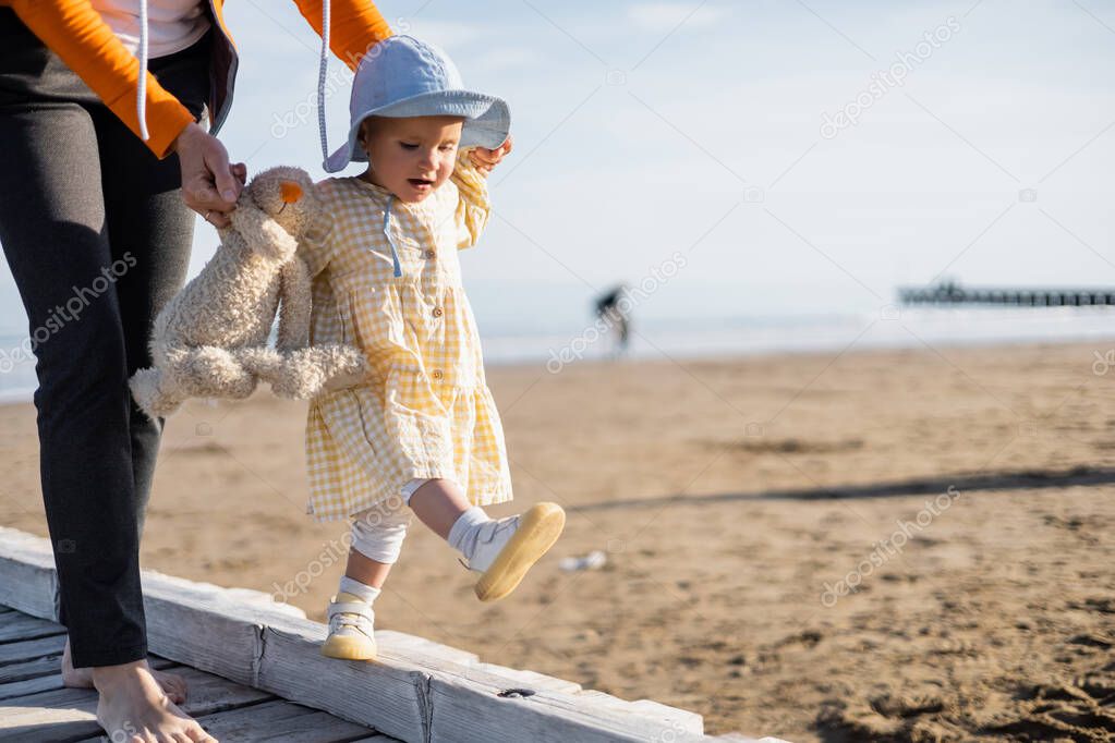 Baby girl walking near mother on pier on beach in Treviso