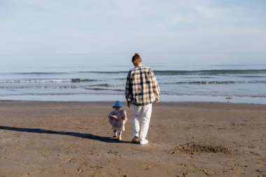 İtalya 'da Adriyatik Denizi yakınlarındaki kumsalda yürüyen baba ve küçük kızın arka görüntüsü. 