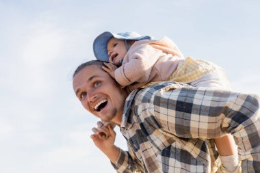Olumlu baba ve bebek arka planda gökyüzü ile eğlenirken düşük açılı görünüm 