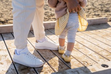 Cropped view of father adjusting pants of baby girl on pier  clipart